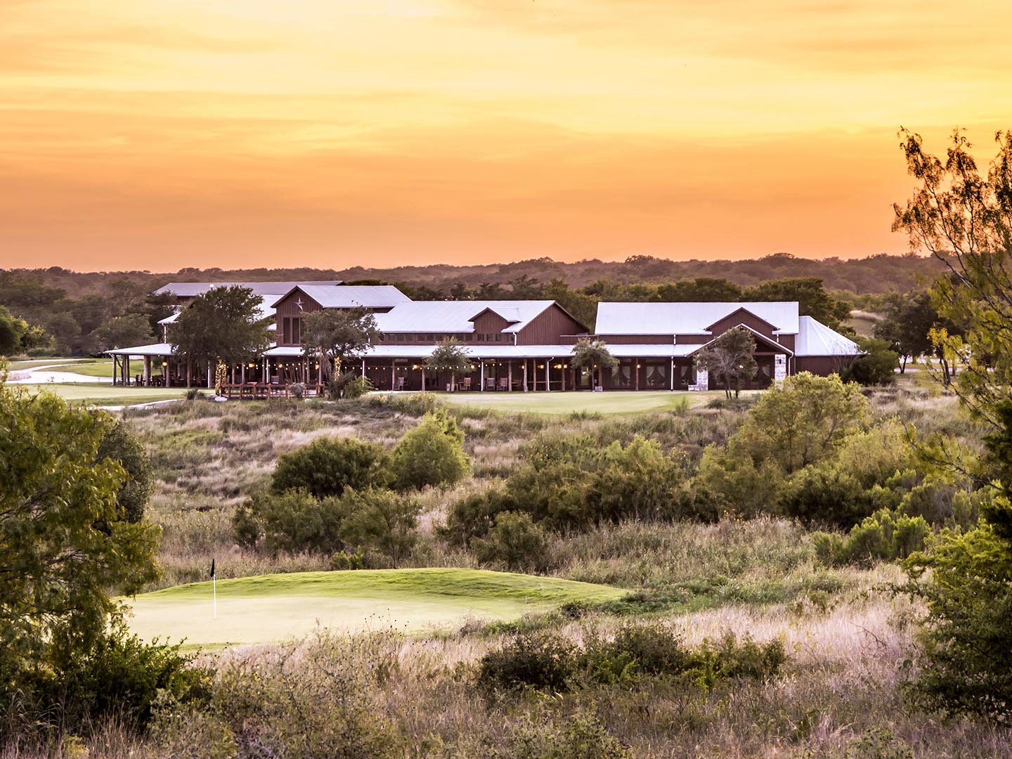 Native grasses and a green below the clubhouse at sunset at The Golf Club of Texas, San Antonio