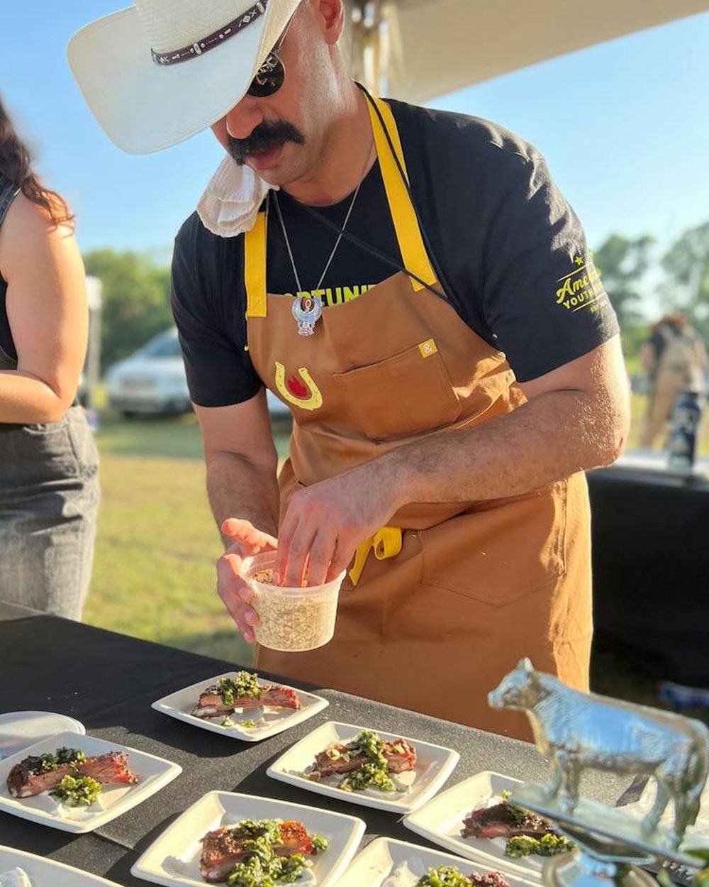 Kareem El-Ghayesh of KG BBQ plating food at an outdoor table
