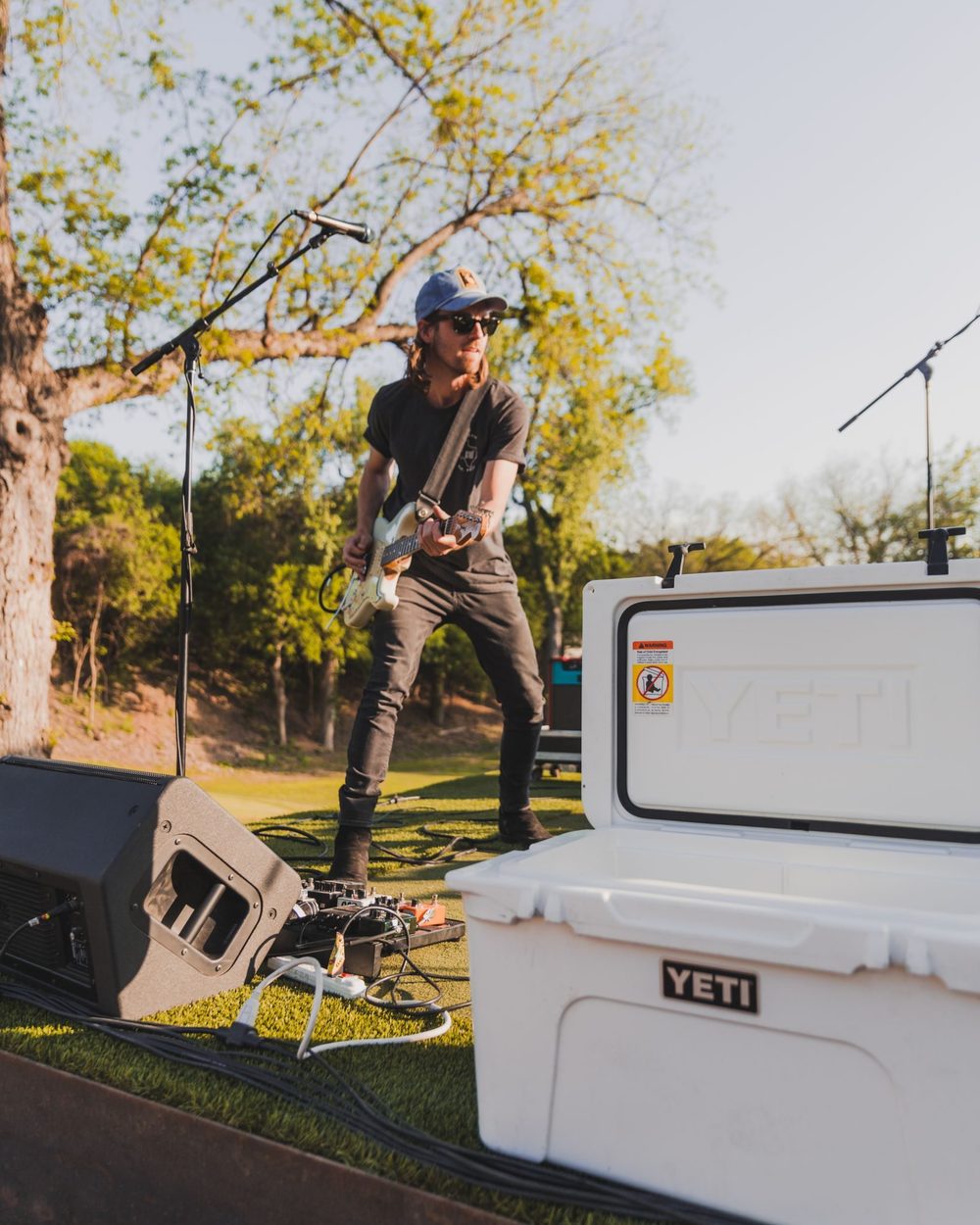 A musician playing guitar beside a cooler at Butler Pitch & Putt