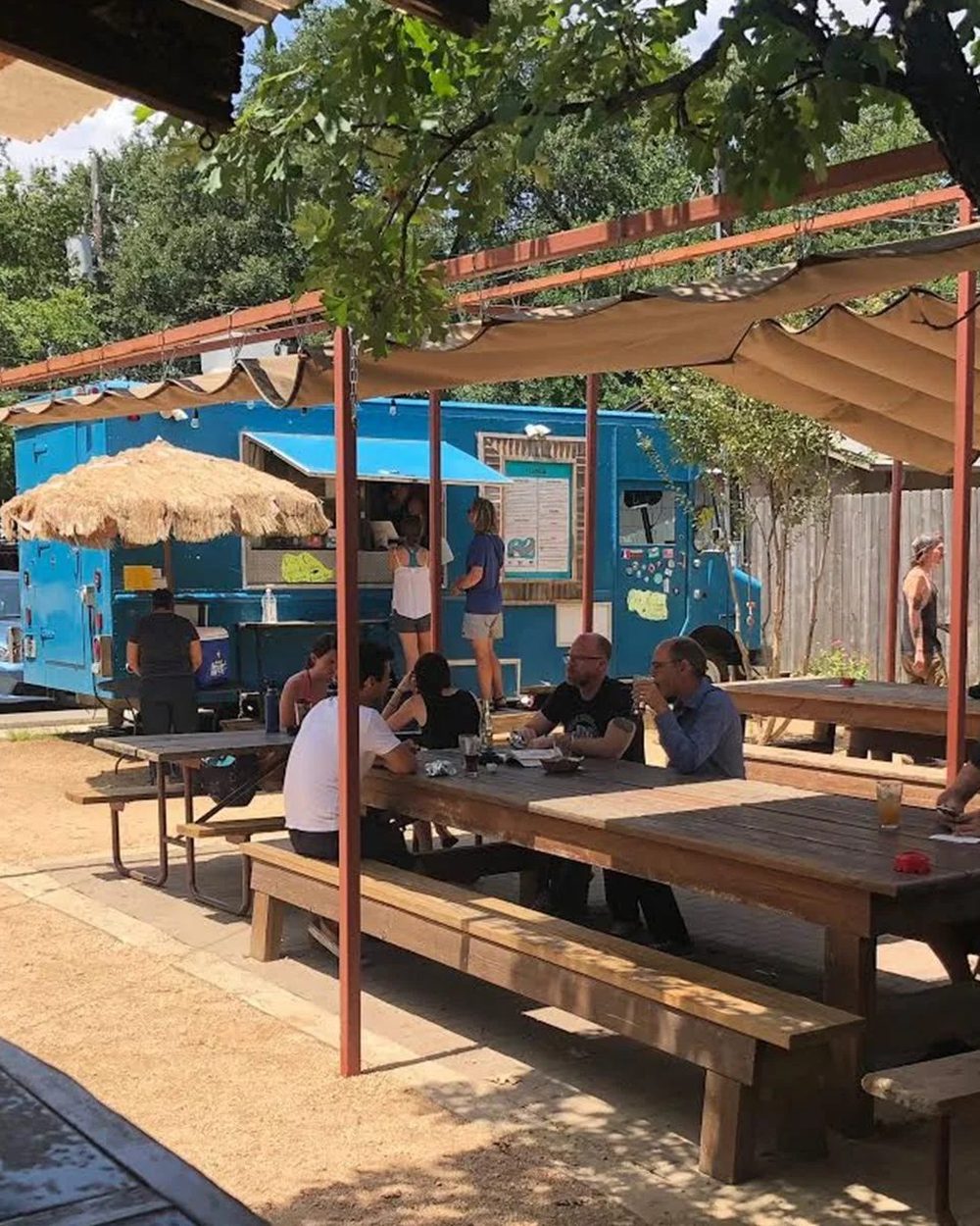 Picnic tables under shade sails at a Veracruz All Natural patio
