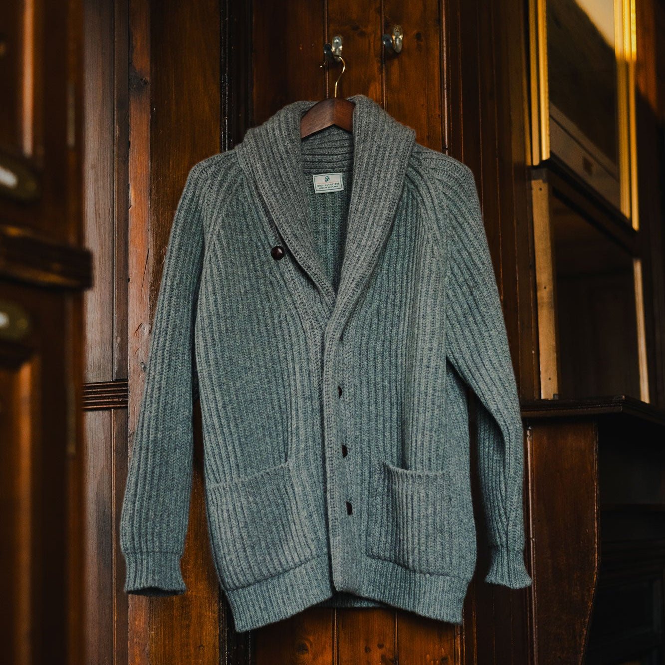 The grey shawl cardigan hanging on a wooden locker