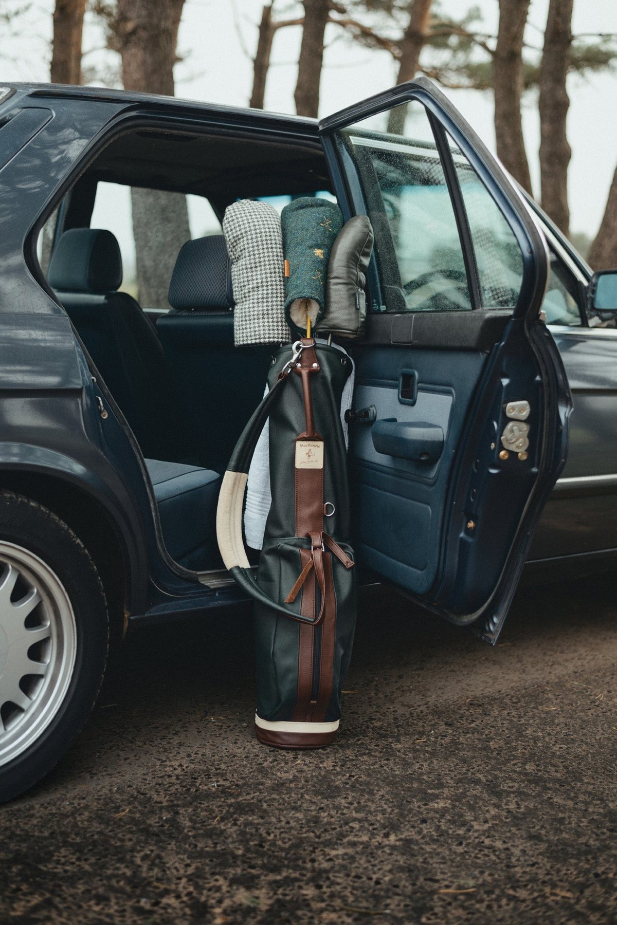 Golf bags in the open back door of the car