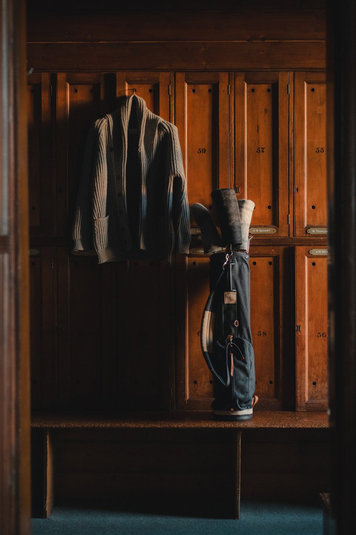 A cardigan and golf bag in an open wooden locker