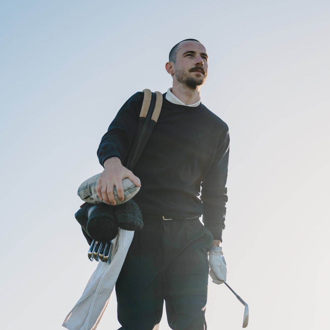 A golfer with his bag against a pale sky