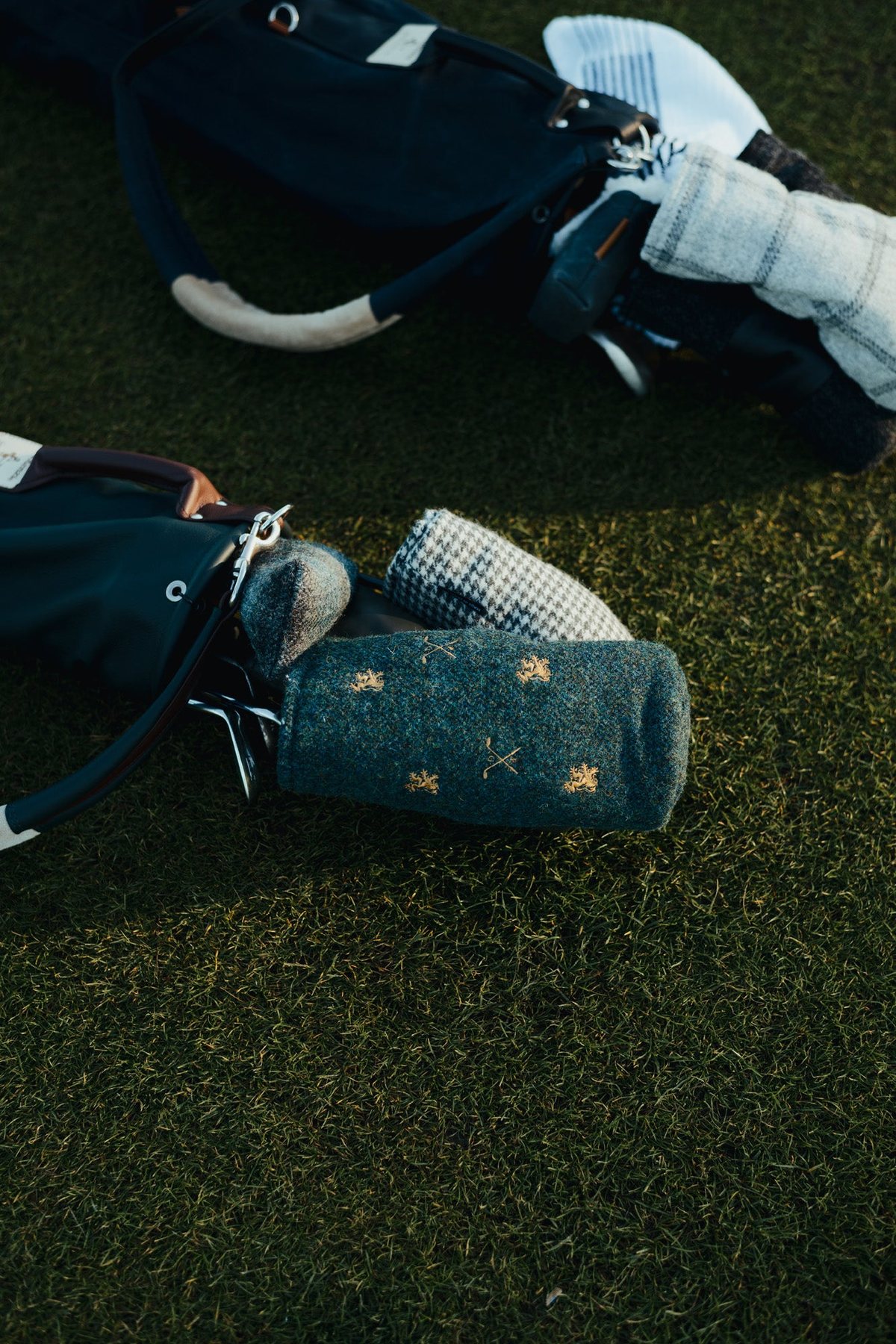 A tweed headcover and glove on the grass beside a bag