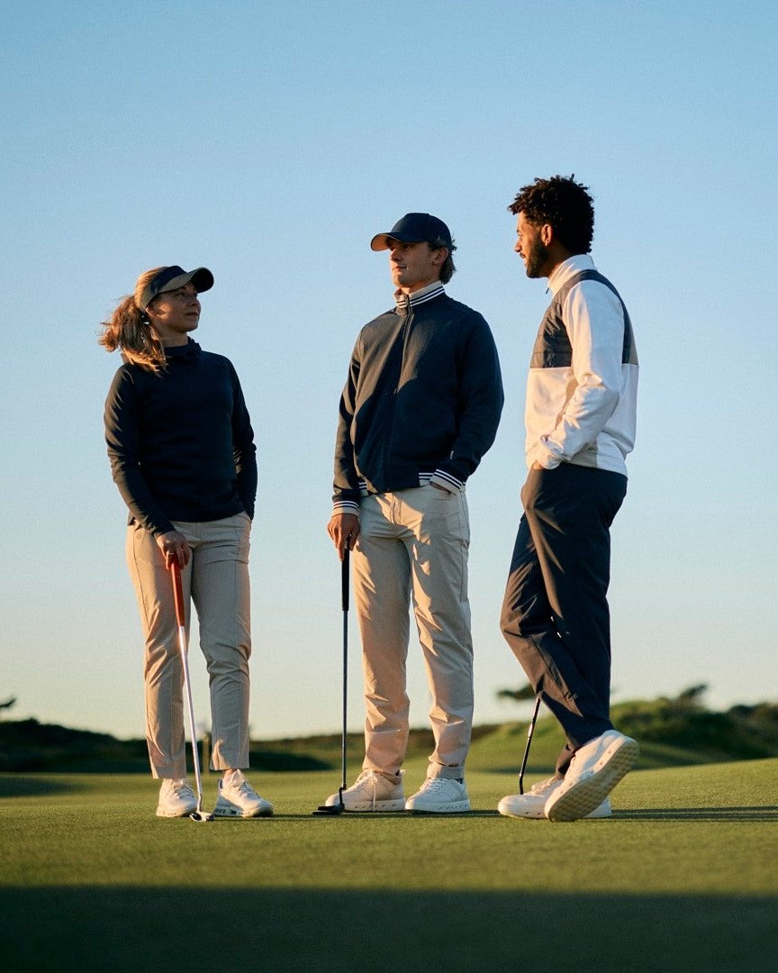 Three golfers talking on a green in Galvin Green INSULA mid-layers and trousers