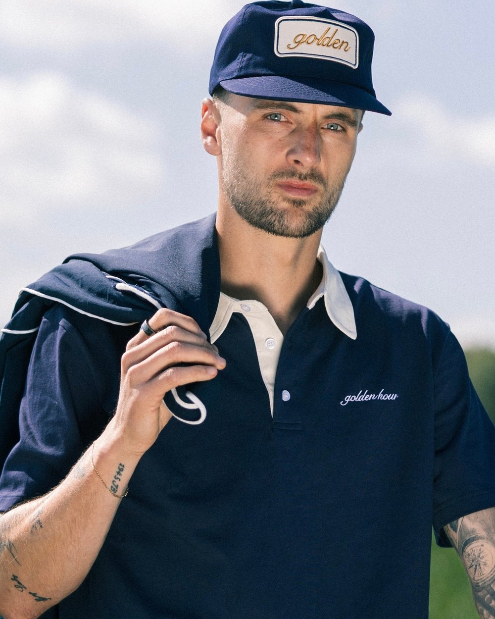 A golfer in the Heritage Polo and a Golden Patch cap with a jacket over his shoulder