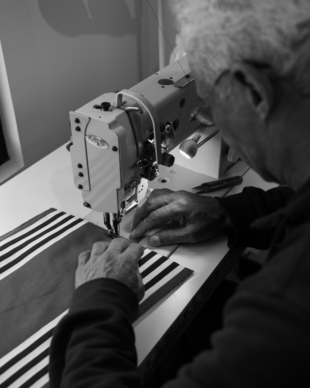 A craftsman sewing leather on an industrial sewing machine