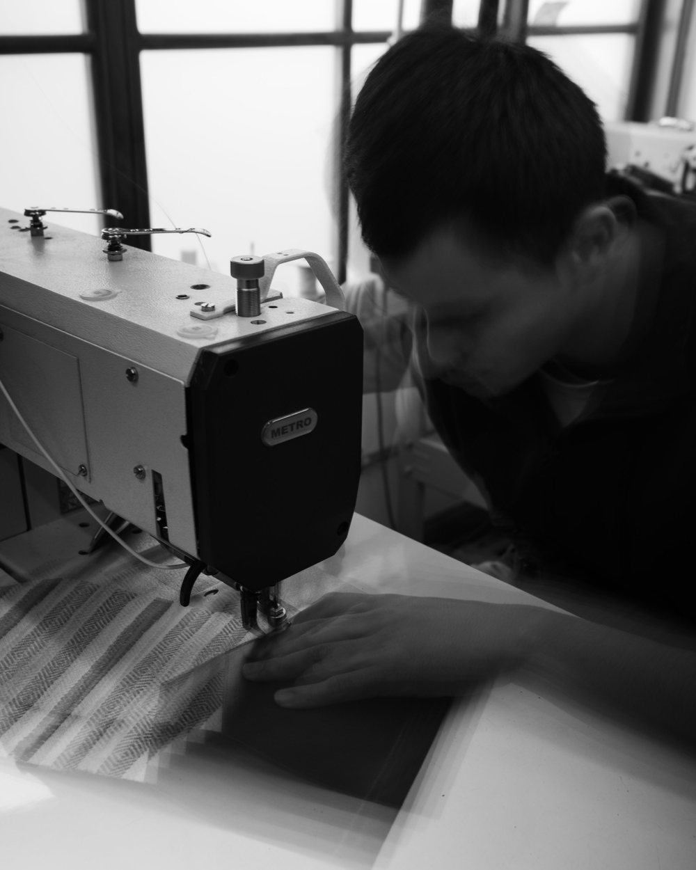 A craftsman sewing at a machine in a bright workshop