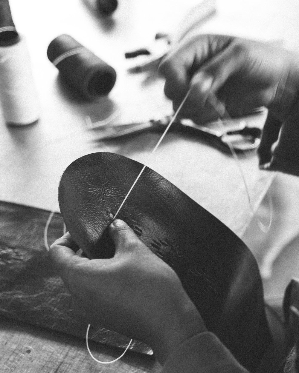 Close-up of hands hand-stitching a leather headcover