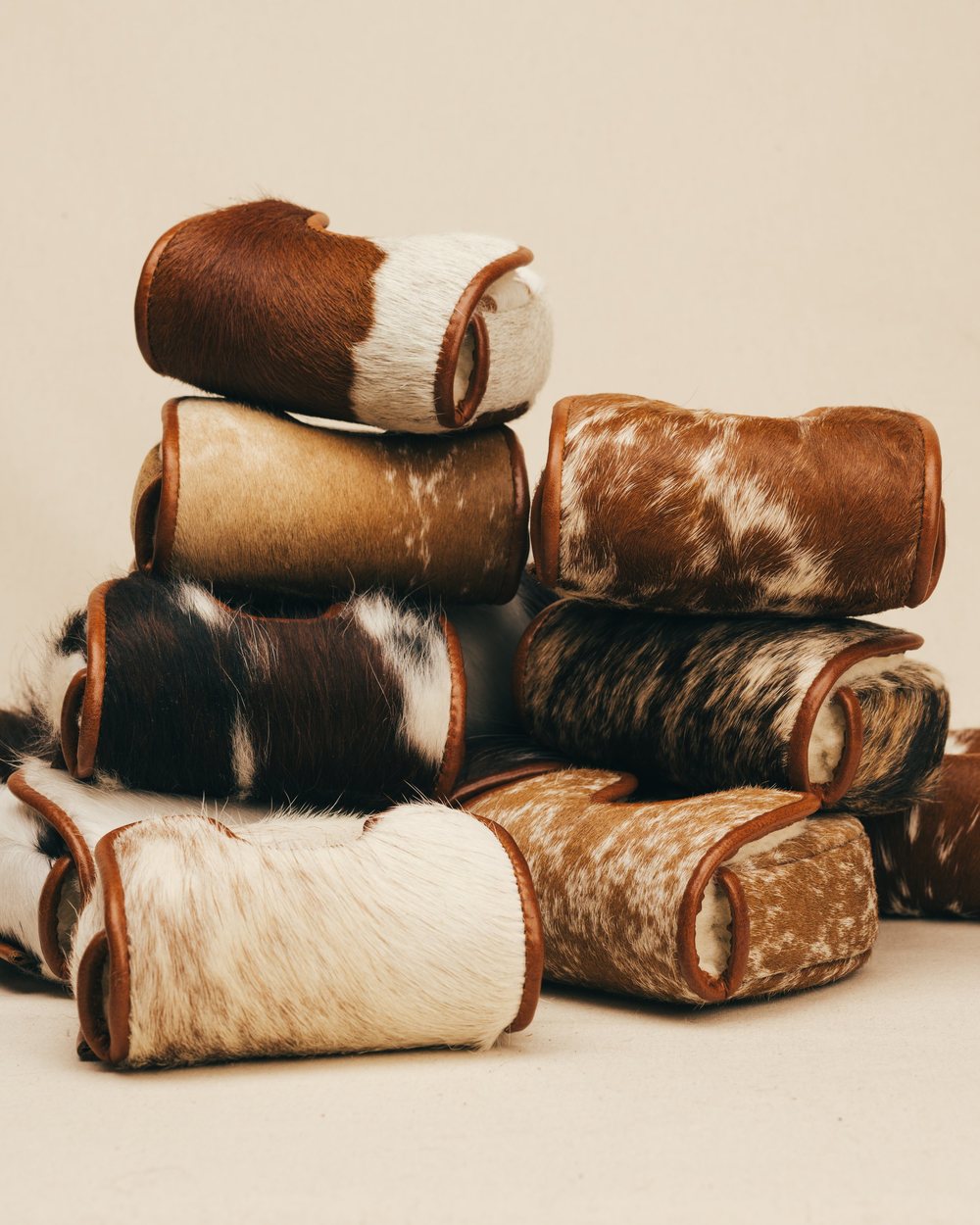 A stack of brown and white cowhide headcovers