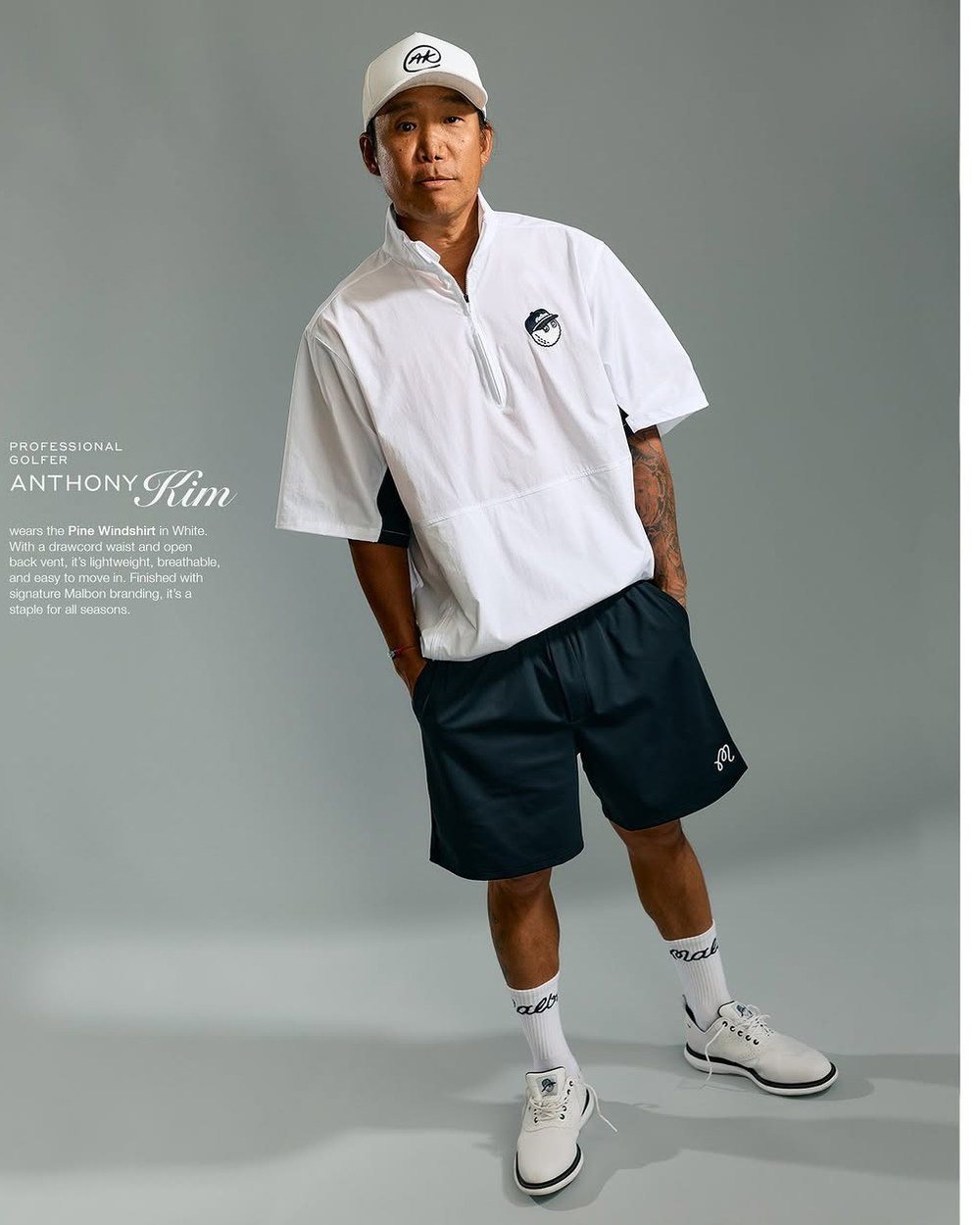 Anthony Kim full length in a white half-zip windshirt, navy shorts and white AK cap