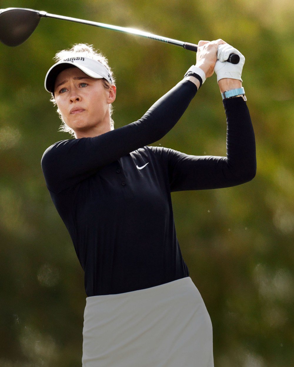 Nelly Korda swinging in a black Nike mock neck and white skirt