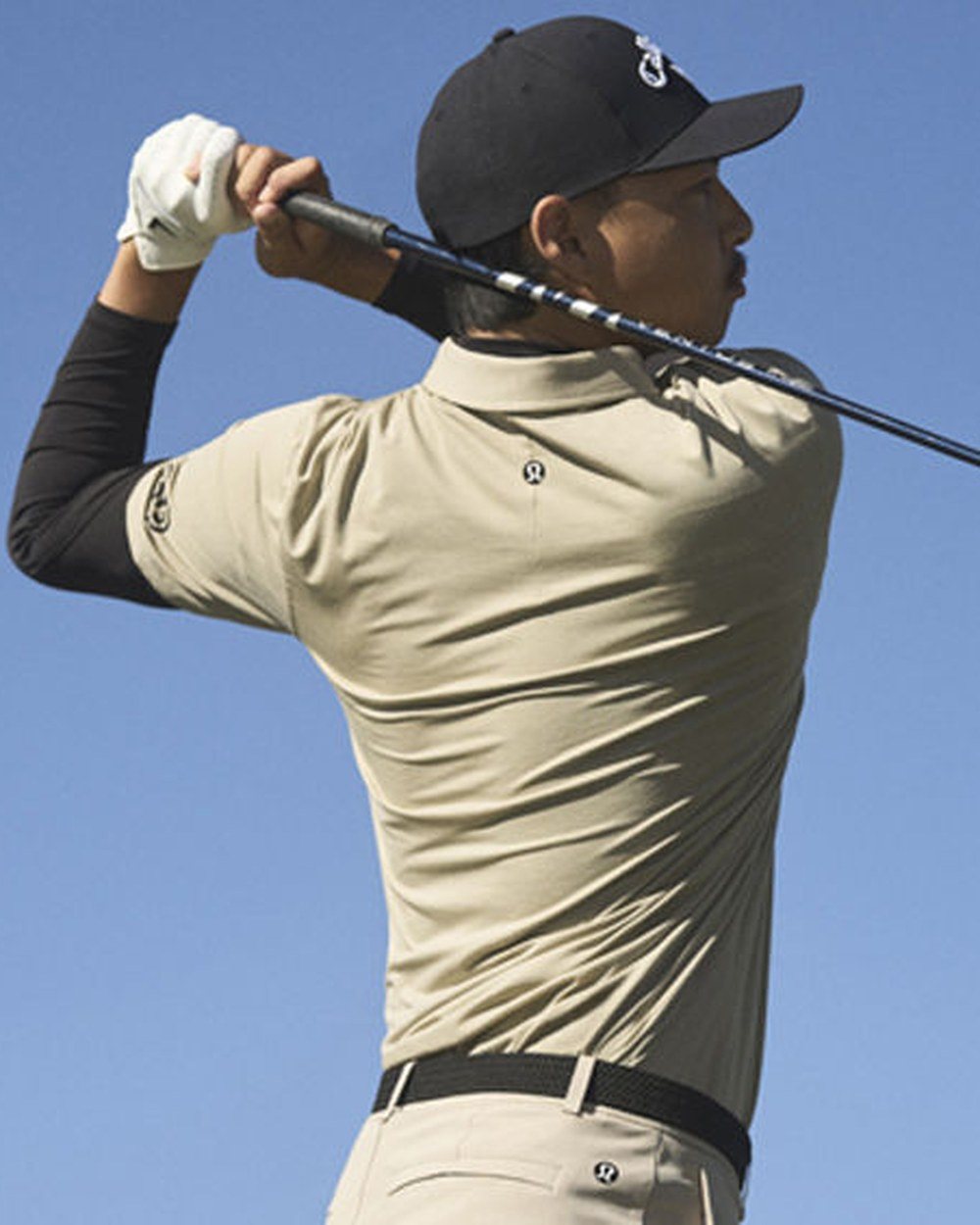 Min Woo Lee swinging in a beige mock neck