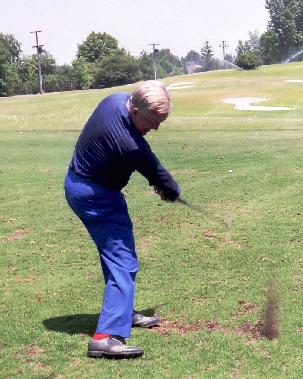 Moe Norman hitting an iron in a blue shirt and bright blue trousers