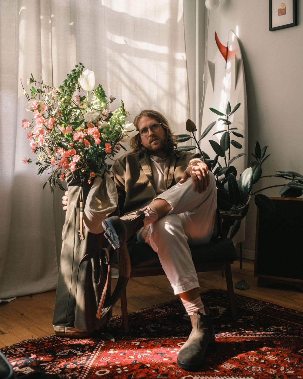 Karsten Jurkschat, founder of Gumtree Golf & Nature Club, seated in his studio holding a golf bag full of flowers