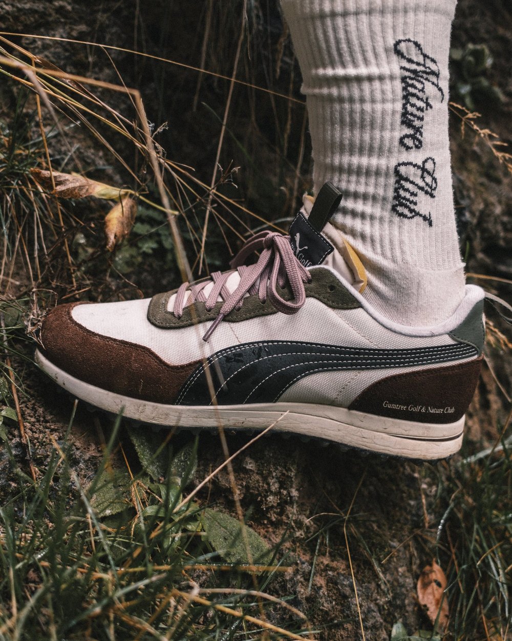 A foot in a Nature Club sock and the GGNC x PUMA Helsinki G shoe in the grass