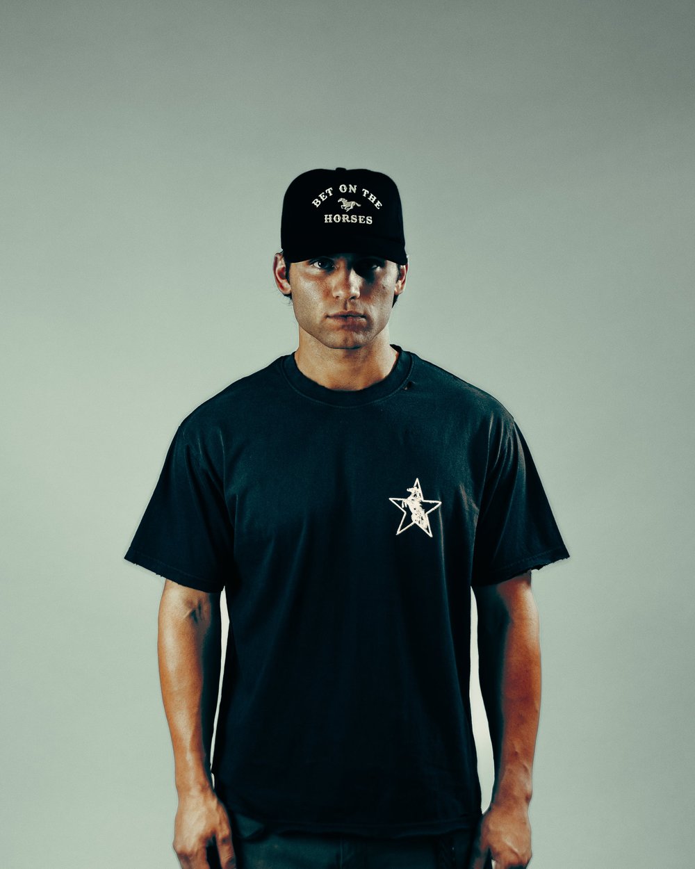 A man in a black B.O.T.H. trucker cap and black tee