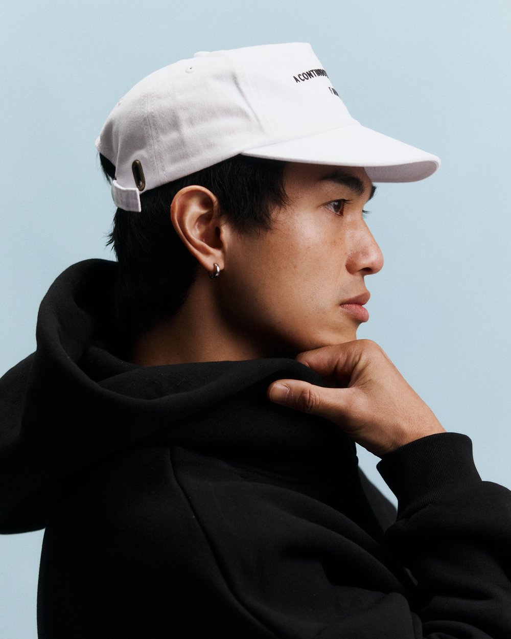 A man in a white F AND CO. cap and black hoodie