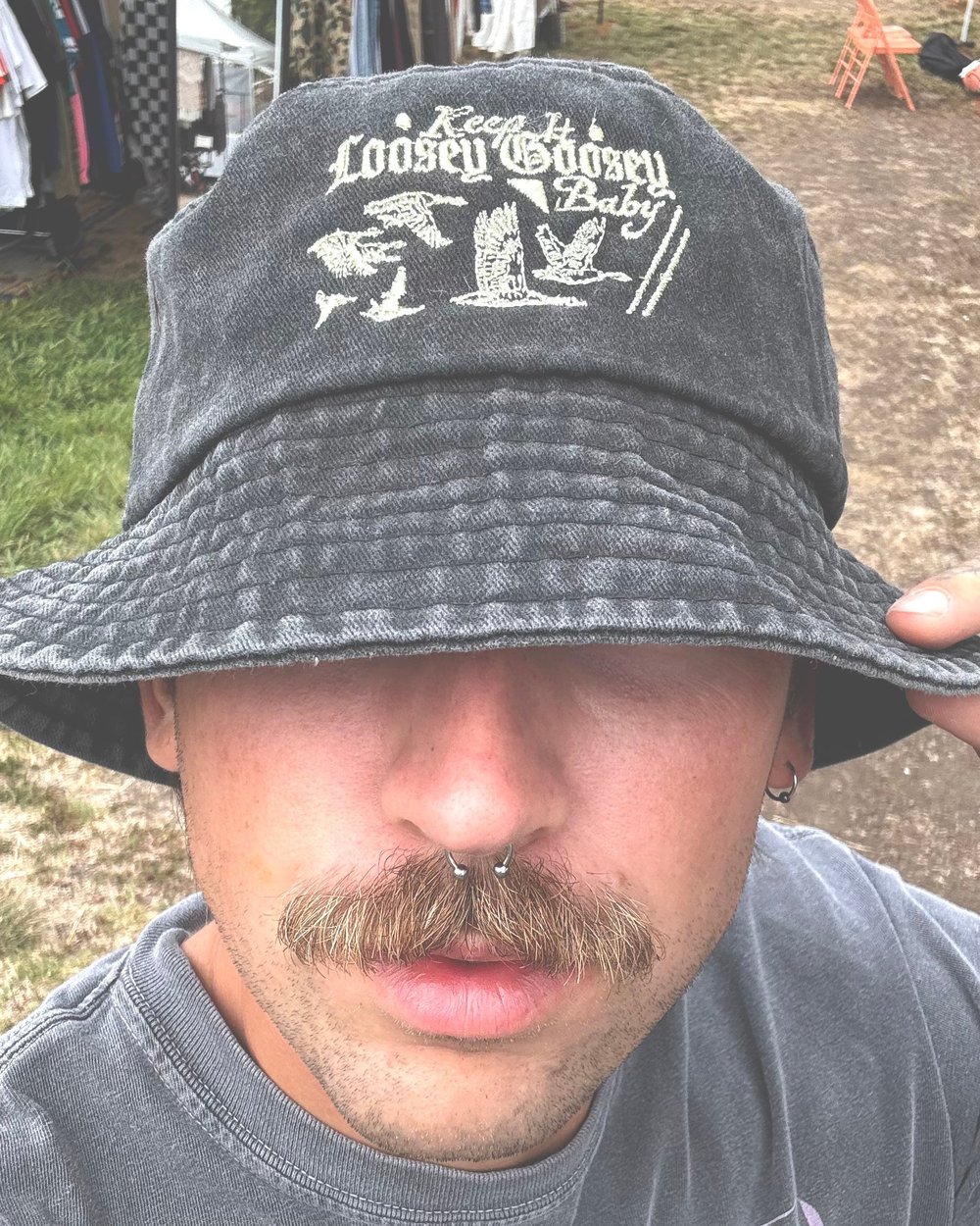 A man in a washed black bucket hat with goose embroidery