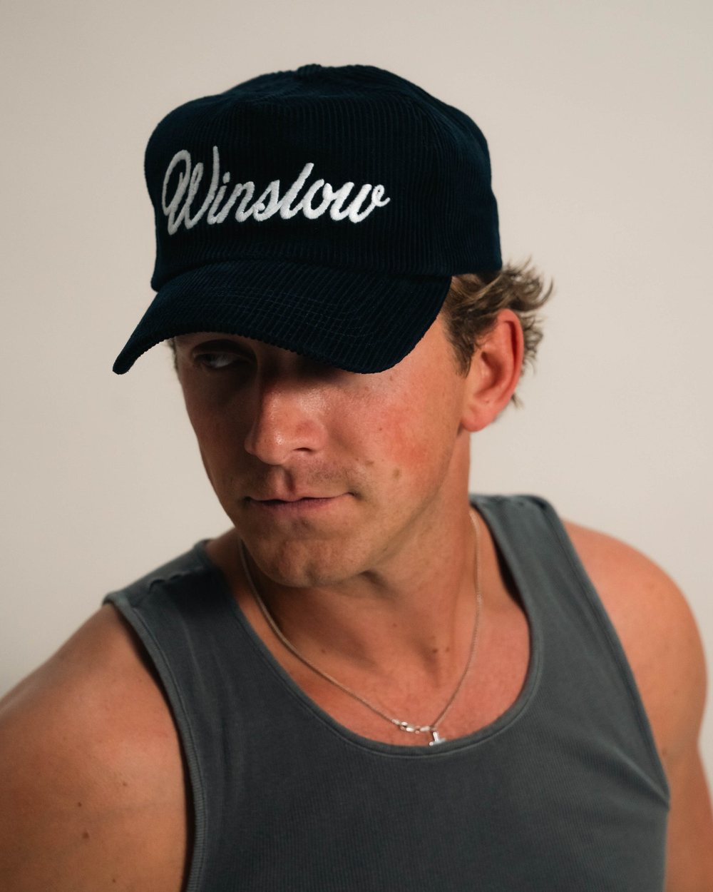 A man in a navy Winslow corduroy hat and a grey tank top