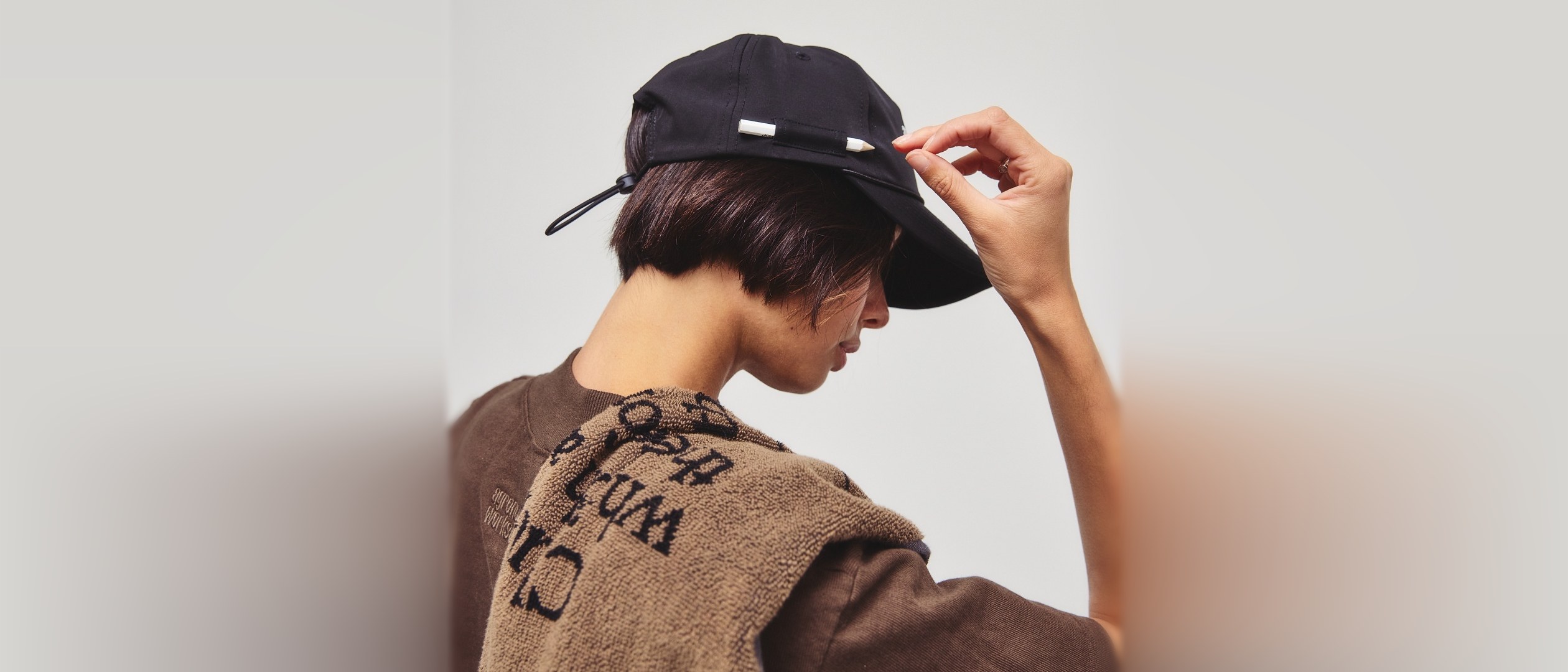 A hand adjusting a black Agronomy Workshop rope hat with a pencil tucked into its side holder