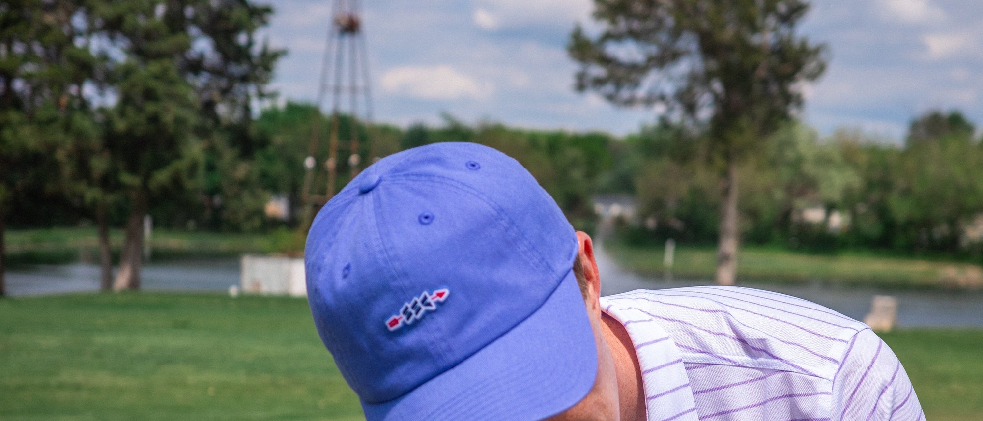 An independent-brand golf cap on course &mdash; the Cotton SSC Arrow Cap from Sugarloaf Social Club