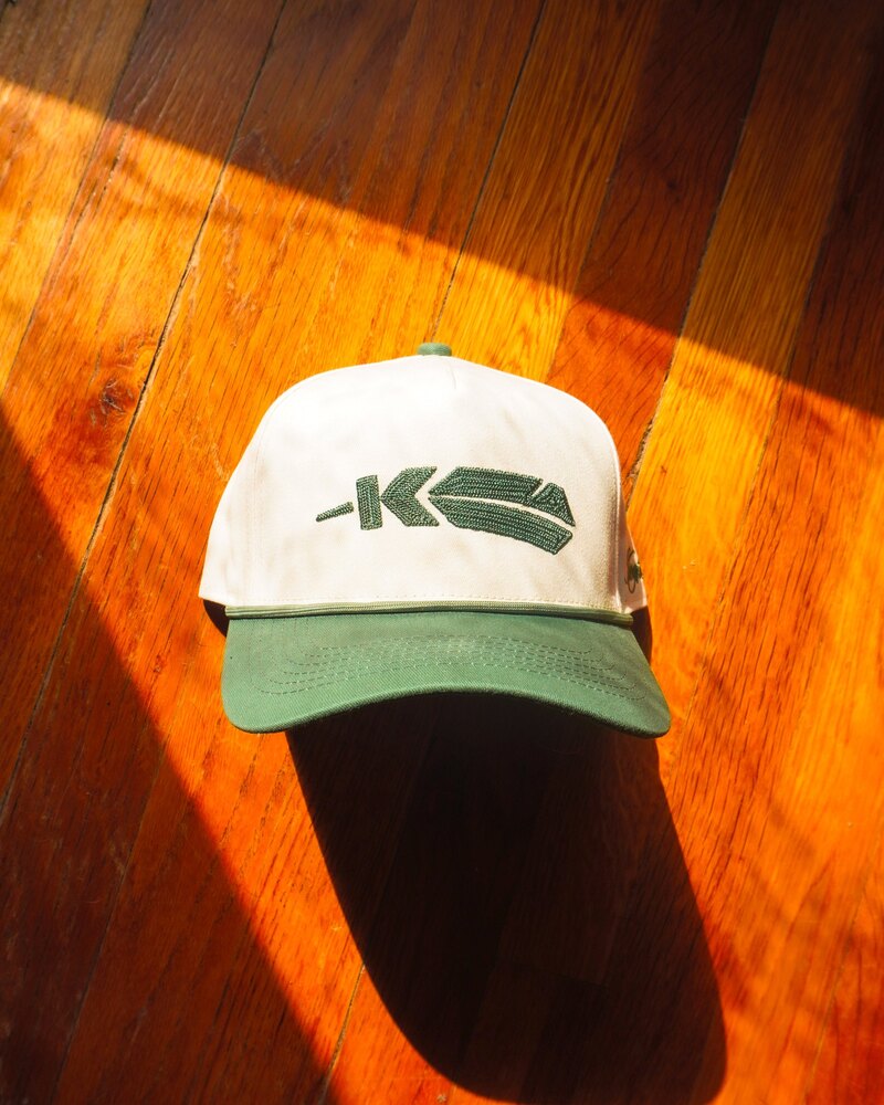 Kingfisher feather logo rope cap on a wood floor