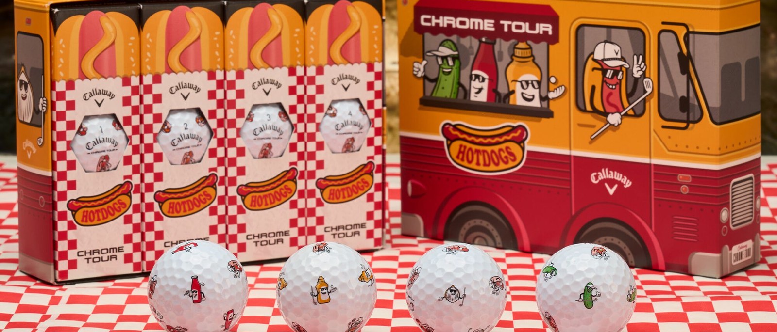 Callaway Chrome Tour Hot Dog golf balls in front of their food-truck boxes on a red checked tablecloth