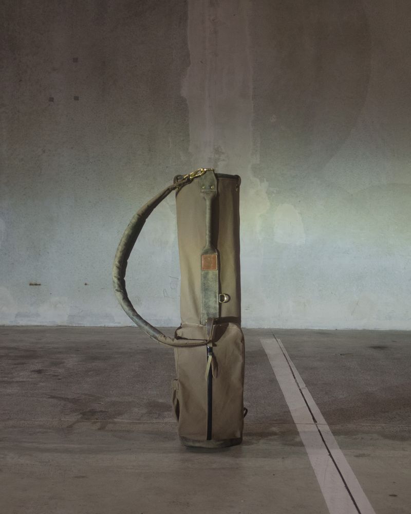 An olive Local GC Sunday bag standing in an empty concrete garage