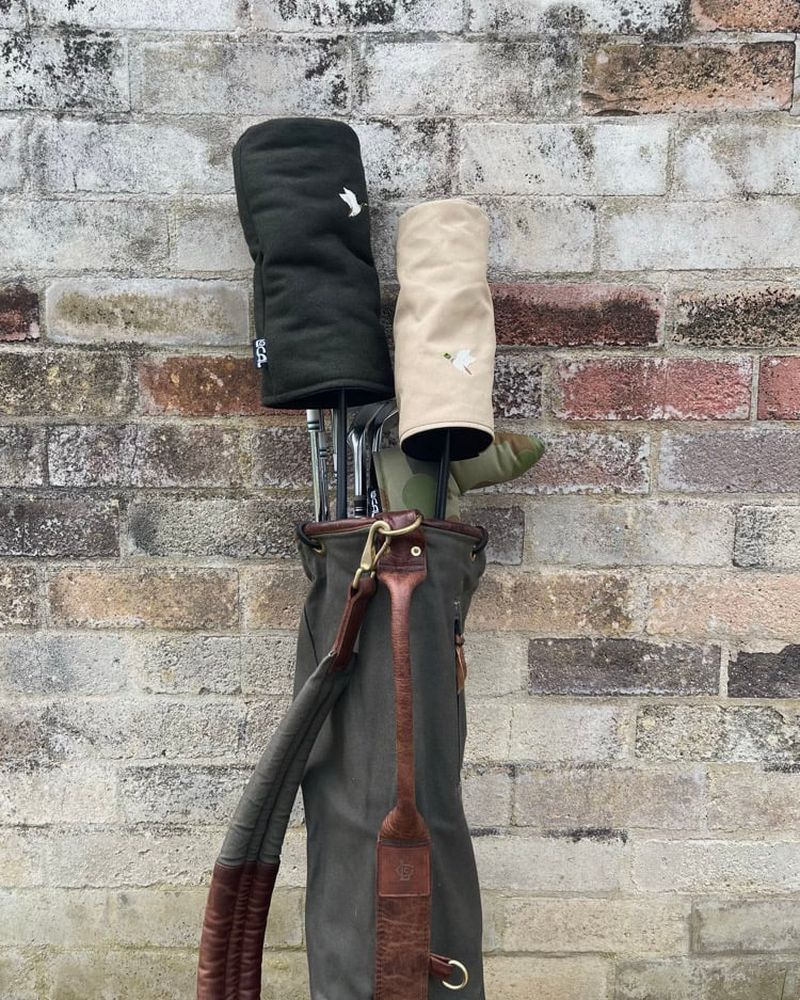 Mallard canvas and wool headcovers on clubs against a brick wall
