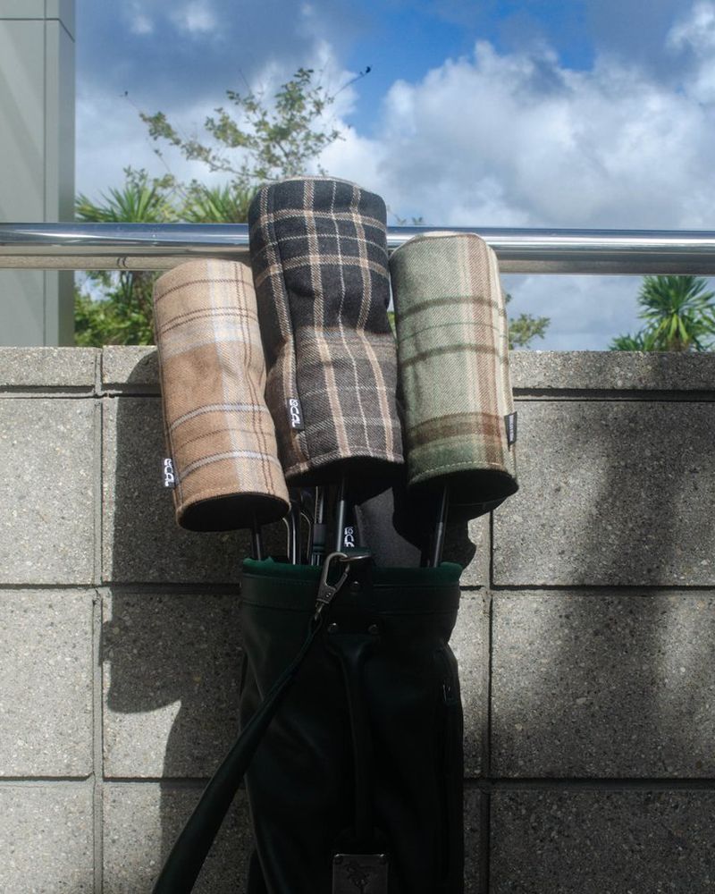 Tartan and check wool headcovers on clubs against a blue sky