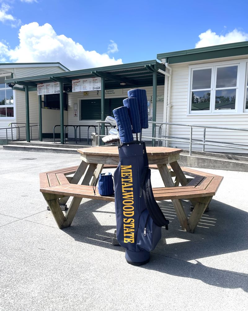 A navy carry bag with matching covers leaning on a schoolyard picnic table