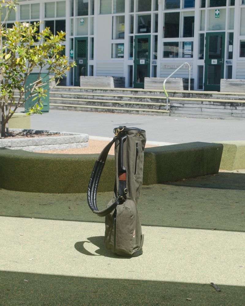 An olive carry bag standing in a schoolyard