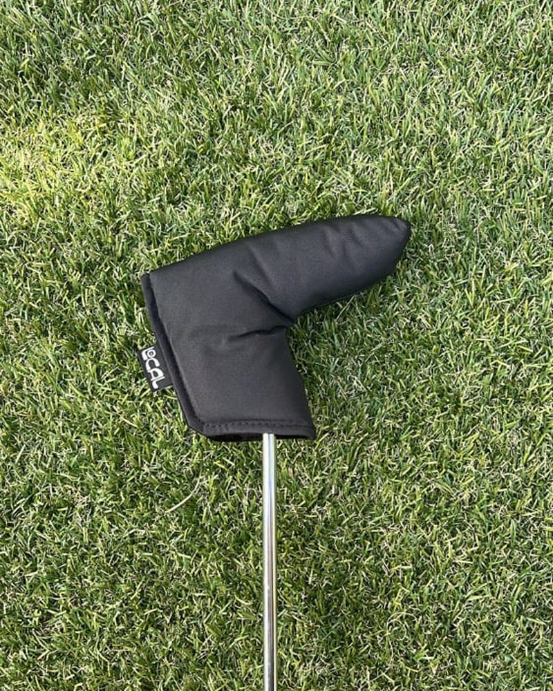A black sailcloth putter cover on a putter on turf