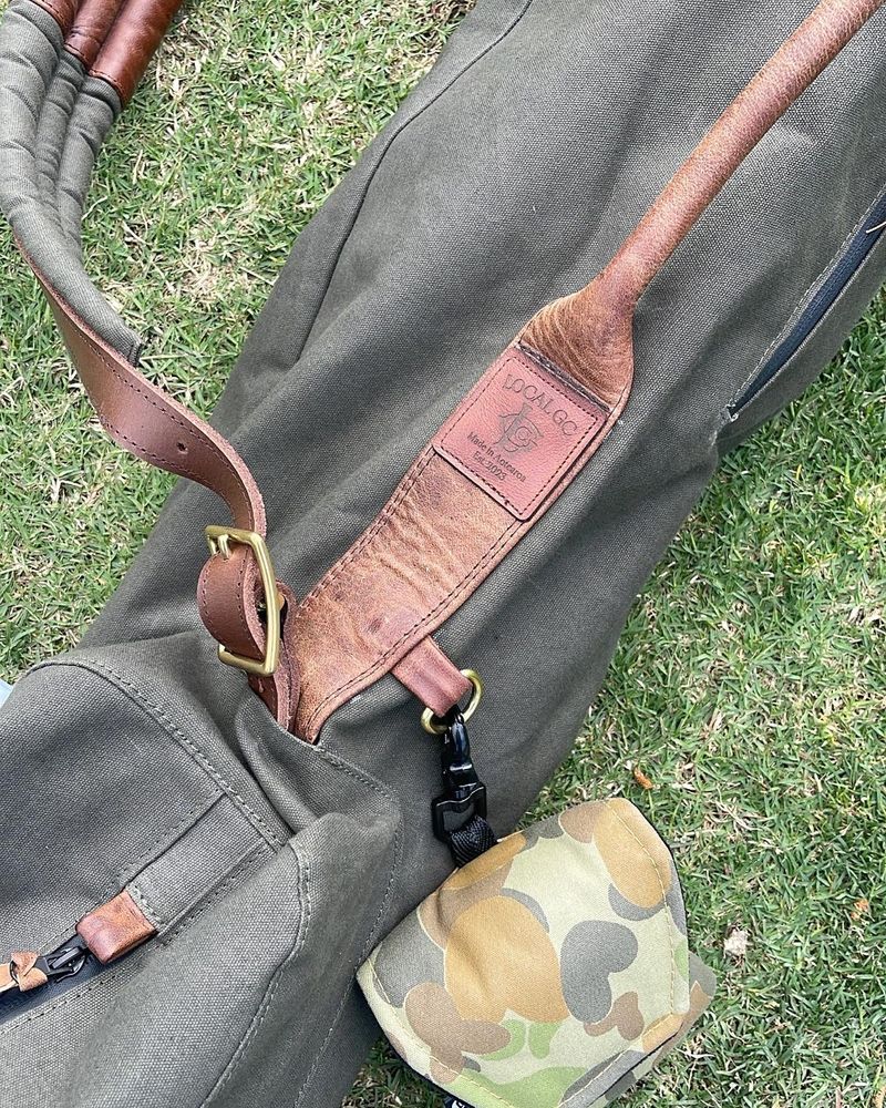 A camo pouch clipped to a canvas carry bag on grass