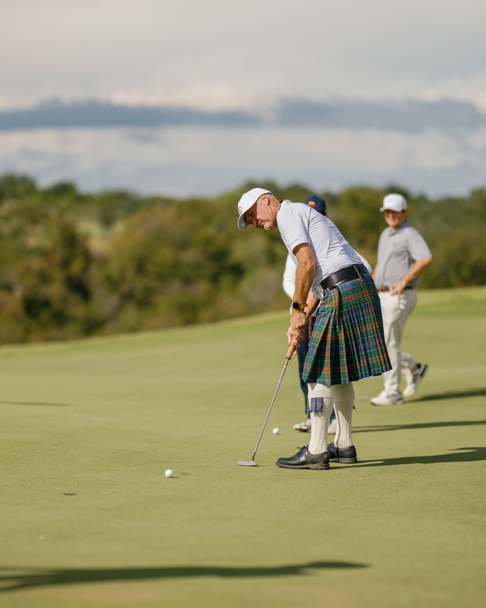 A golfer in a kilt putting on a Loraloma green at the opening event
