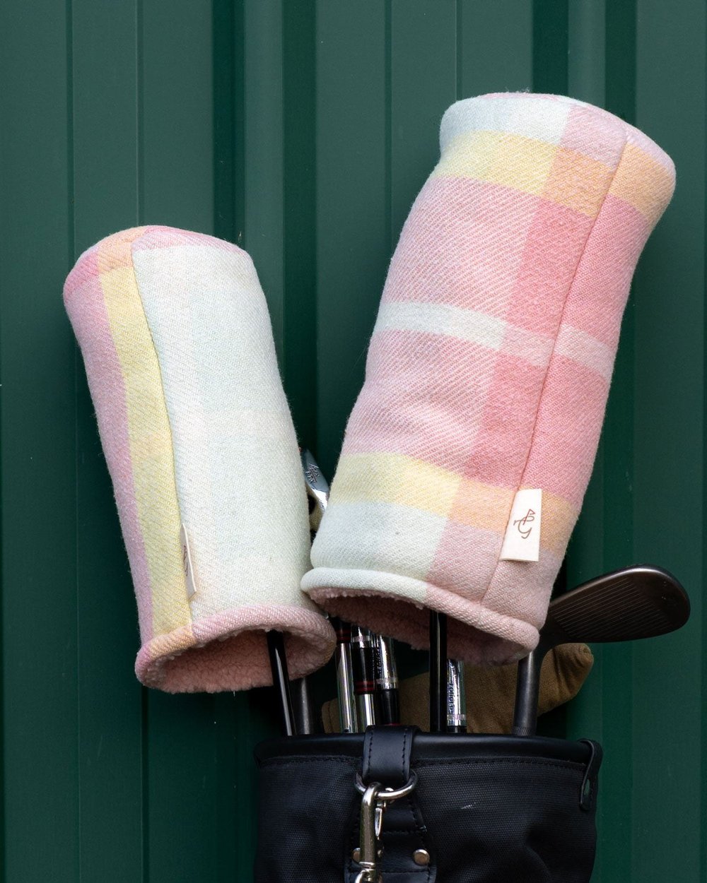 Pastel check headcovers on a bag against a green wall