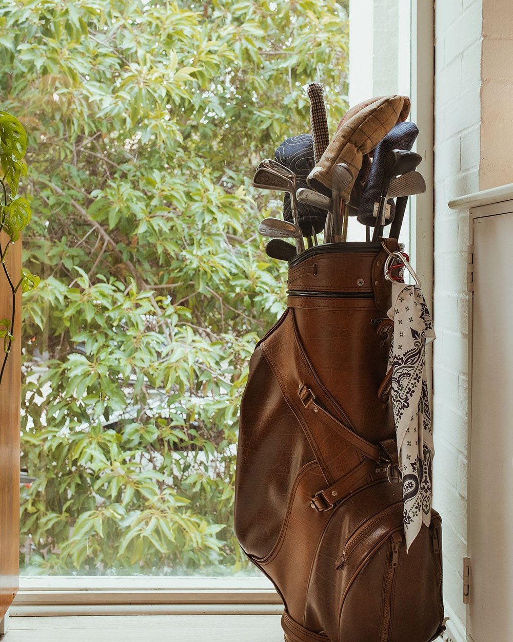 An old leather golf bag by a window