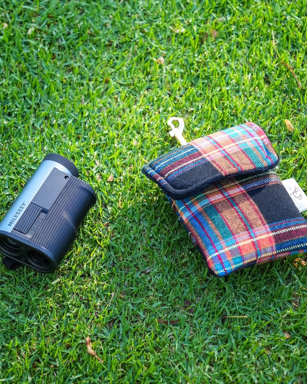 A tartan rangefinder pouch and a rangefinder on the grass