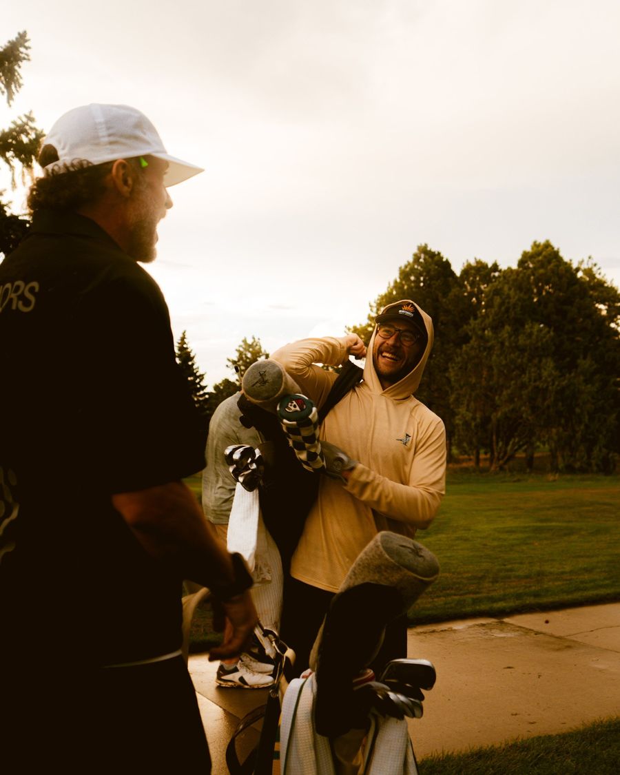 Two golfers by their bags at a Denver course, one in the Magpie sun shirt