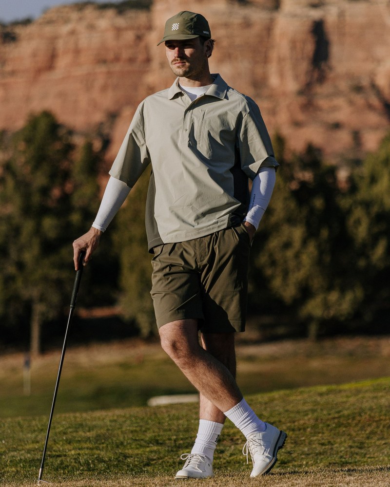 A golfer in Manors walking a desert course beneath a red rock wall