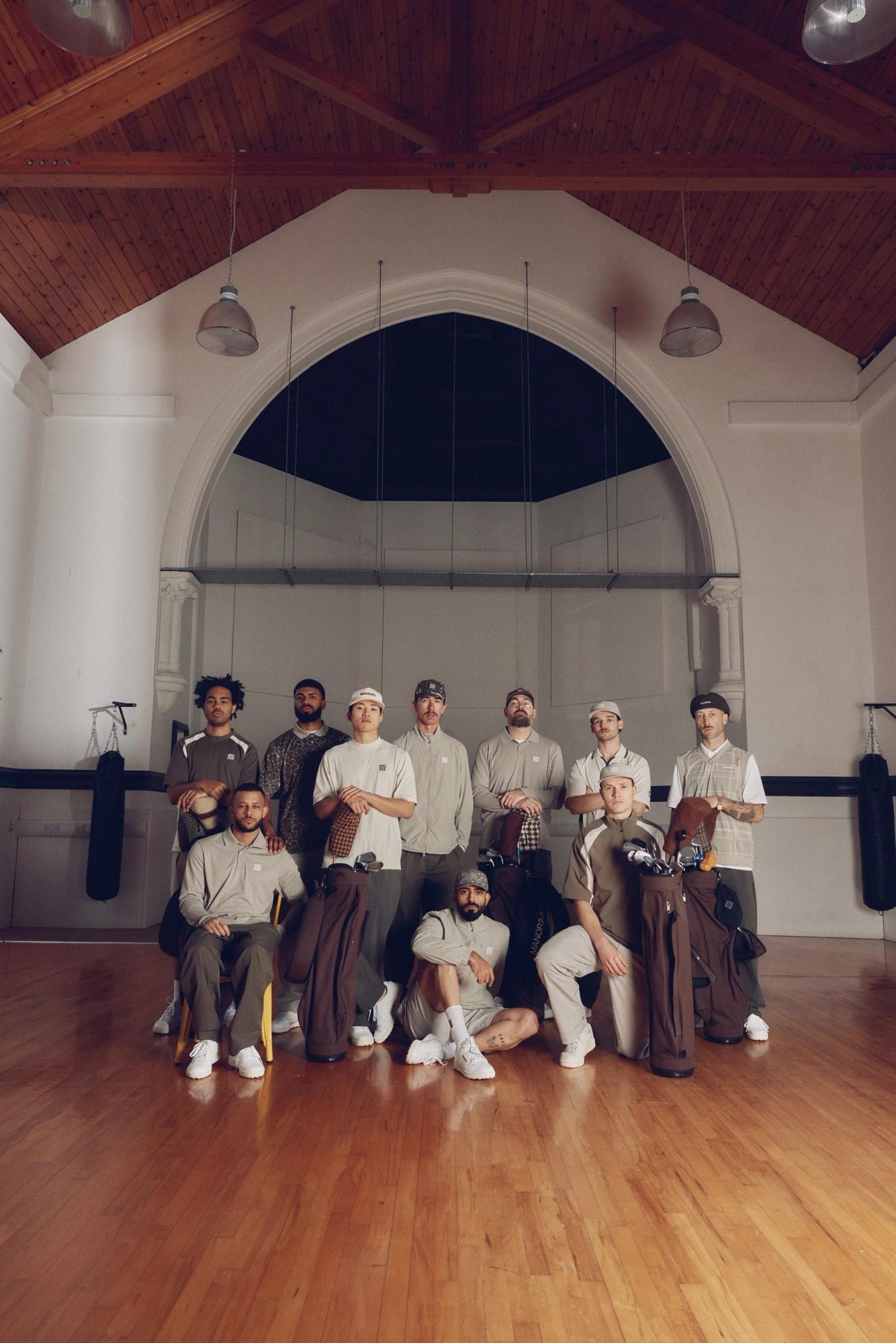 A group portrait of around fifteen people in Manors clothing inside a wood-floored hall
