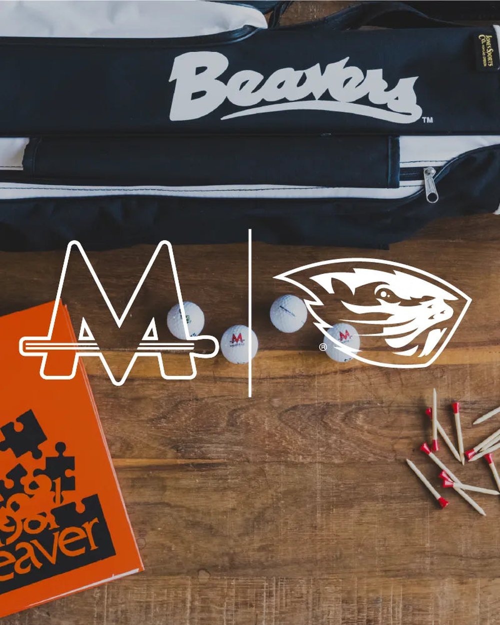 Oregon State Beavers headcovers and ball markers laid out on a wood table with tees