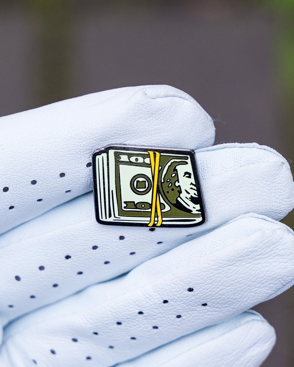 The Cash Stack ball marker resting in the palm of a white golf glove