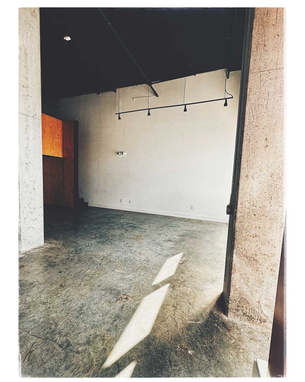 An empty loft space with concrete floors and a big window before Matchstick moved in