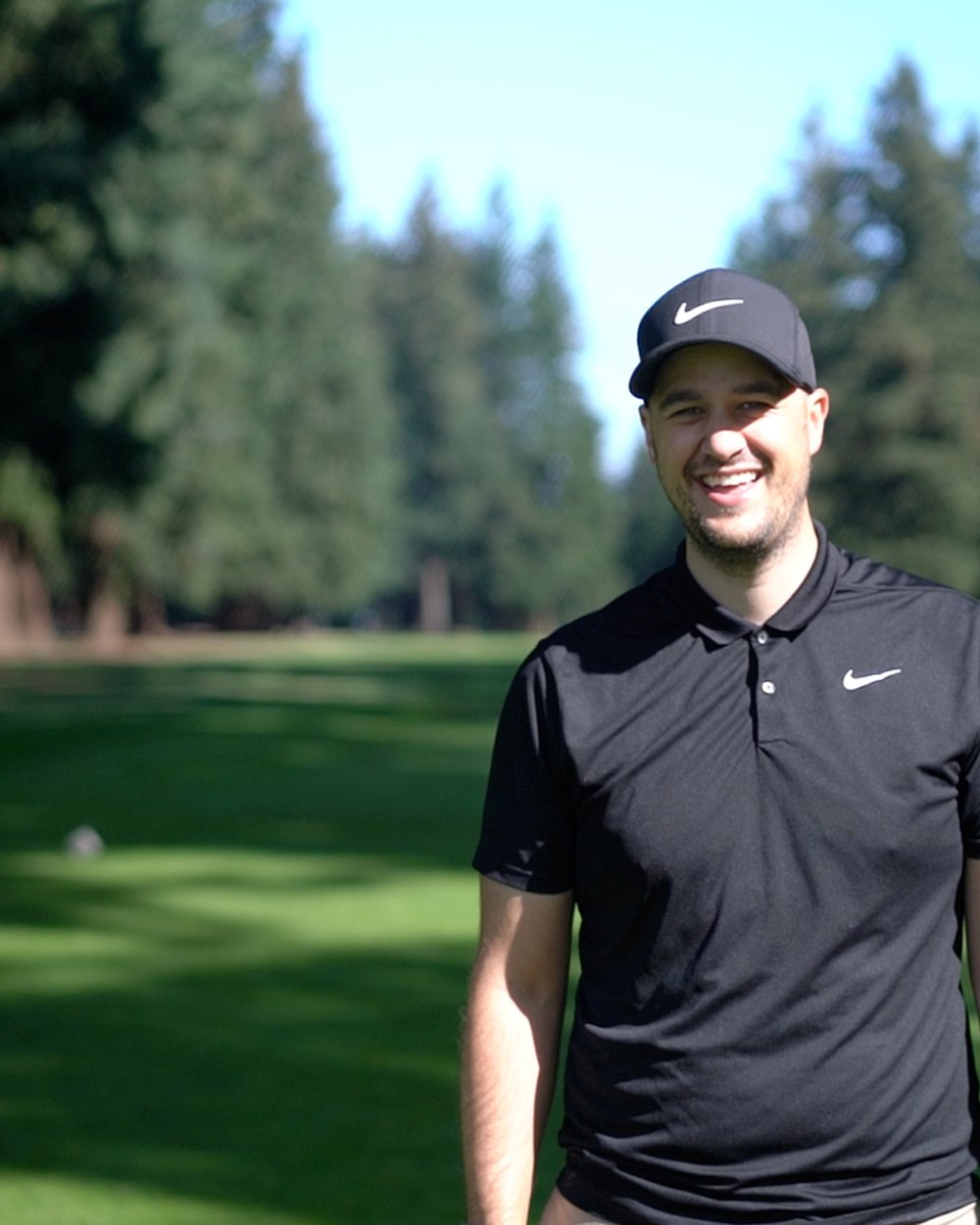 Dane Delgado standing on a fairway lined with tall firs