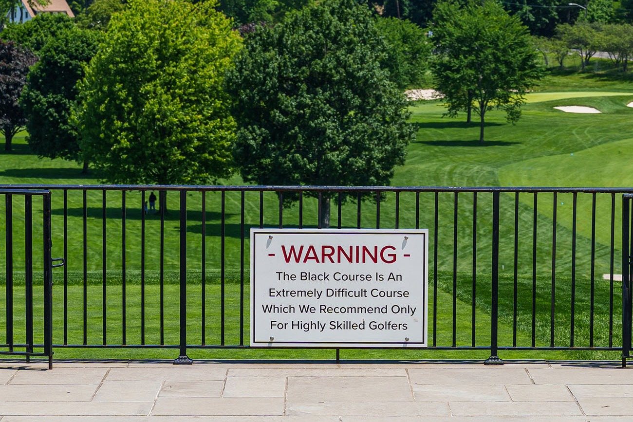 The warning sign on a railing by Bethpage Black's first tee