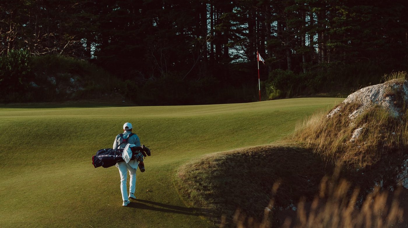 A golfer carrying his own bag up Cabot Cliffs' 14th fairway