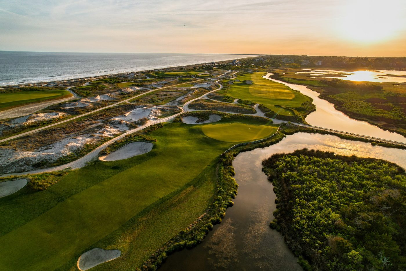 Sunset aerial of fairways between salt-marsh creeks and the Atlantic beach at Kiawah
